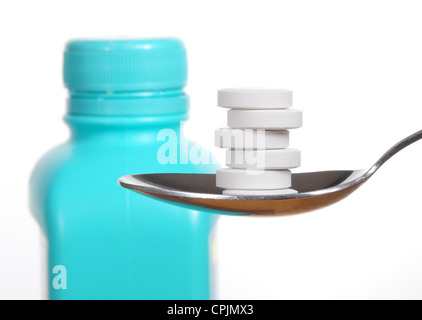 Antacidum Tabletten auf einem Löffel, eine Flasche von Antazida verschwommen im Hintergrund Stockfoto