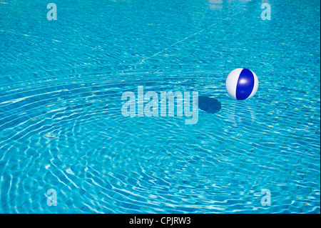 Schwebende blaue und weiße Beachball im Schwimmbad Stockfoto