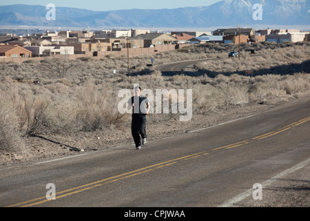 Athletische Hispanic junger Mann läuft neben einer Straße am Stadtrand von Albuquerque, New Mexico. Stockfoto