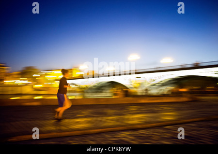 Panning Shot eines Läufers von Triana-Brücke in der Abenddämmerung, Sevilla, Spanien Stockfoto