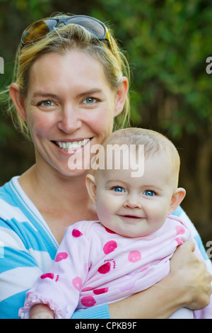 Attraktive Mutter umarmt niedlichen Babymädchen Stockfoto