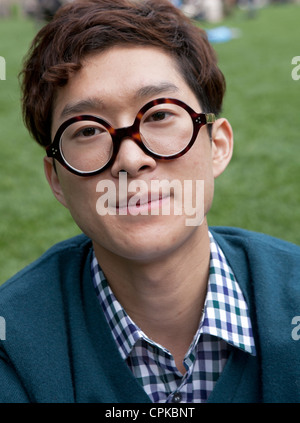 Ein junger Mann mit großer, runder Brille verbringt viel Zeit im Bryant Park in New York City. Stockfoto