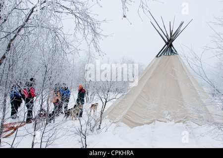 Menschen stehen vor einer traditionellen Sami Lavvu Zelt in Lappland nach einem husky Hundeschlitten Reise Stockfoto