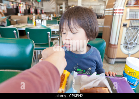 Ein kleiner asiatischer junge gefüttert in einem diner Stockfoto