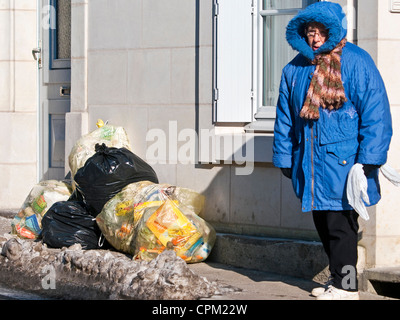 Taschen von Müll blockierende Frau auf Bürgersteig - Frankreich. Stockfoto