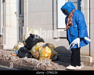 Taschen von Müll blockierende Frau auf Bürgersteig - Frankreich. Stockfoto