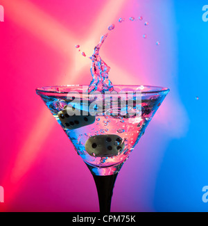 Würfel fallen in ein Glas mit Martini. Stockfoto