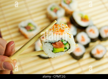 Hand halten Sushi. Japanische traditionelle Speisen. Bambus-Serviette im Hintergrund Stockfoto