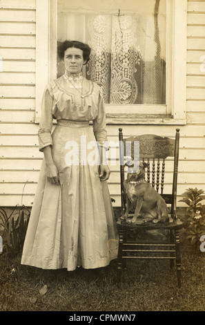 Gut gekleidete junge Frau im Freien mit Hund auf Stuhl sitzend Stockfoto