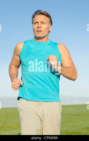 Ein Mann in einem Feld trägt einen blauen Tank Top zum Joggen. Stockfoto