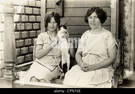 Mutter & Tochter auf Veranda Schaukel mit Katze Stockfoto