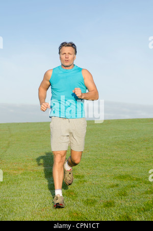 Ein Mann in einem Feld trägt einen blauen Tank Top zum Joggen. Stockfoto