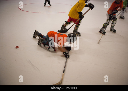 Zehn Jahr fällt alten Rollhockey-Spieler während eines Spiels. Stockfoto