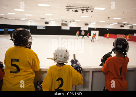 Junge Hockeyspieler beobachten Teamkollegen auf der Eisbahn. Stockfoto