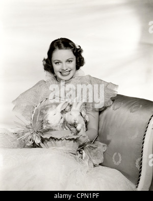 Lächelnde Schönheit mit zwei Kaninchen in einem Osternest Stockfoto