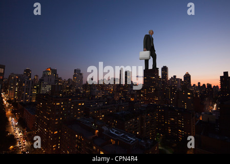 Riesige Geschäftsmann stand am Anfang von Wolkenkratzer in der Abenddämmerung Stockfoto