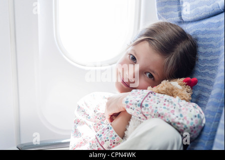 Mädchen hält Stofftier auf Flugzeug, Porträt Stockfoto