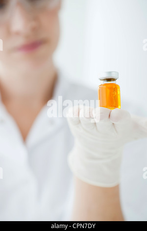 Wissenschaftler halten Fläschchen mit orange Flüssigkeit Stockfoto