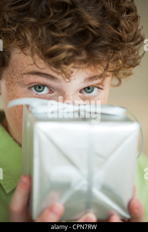 Preteen Boy Holding verpacktes Geschenk vor Gesicht Stockfoto