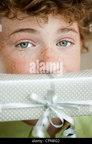 Junge mit Geschenk vor Mund, Porträt Stockfoto