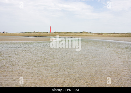 Bach an einem Strand bei Ebbe, in den Dünen entfernt und ein roter Leuchtturm. Stockfoto