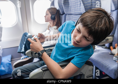 Junge aus Sitz stützte sich auf Flugzeug Gang hinunter schauen Stockfoto