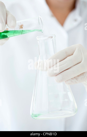 Wissenschaftler Gießen Flüssigkeit aus Messzylinder in konischen Kolben Stockfoto