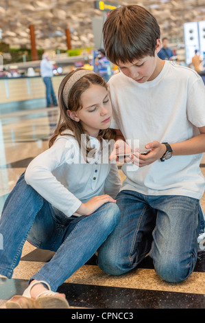 Bruder spielt mit Handy, Schwester beobachtet mit Interesse Stockfoto