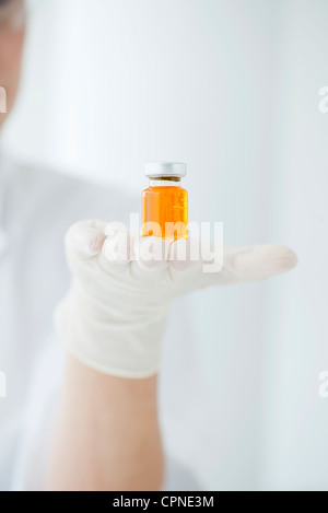 Wissenschaftler halten Fläschchen mit orange Flüssigkeit Stockfoto