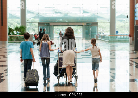 Familie schieben Gepäckwagen am Flughafen, Rückansicht Stockfoto