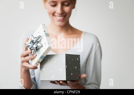 Junge Frau, die Geschenkbox zu öffnen Stockfoto