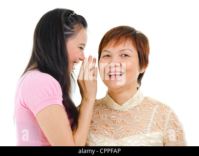 Junge asiatische Tochter heimlich im Gespräch mit ihrer Mutter Stockfoto