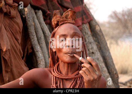 Die Himba Matriach sitzt und genießt ihre Pfeife. Stockfoto