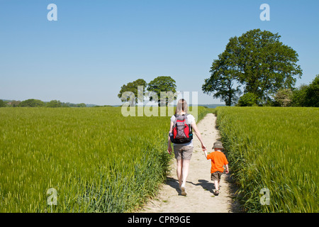 Mädchen und Jungen zu Fuß durch eine Ernte von Gerste auf einem Kreide-Pfad in der Nähe von Buriton auf der South Downs in Hampshire Stockfoto