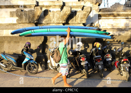 Balinesische Mann mit Vermietung Surfbretter kehrt heim nach einem Tag am Strand von Kuta. Stockfoto