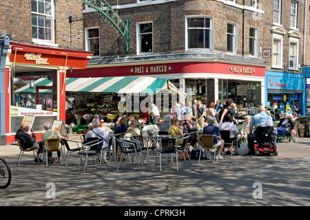 Menschen Touristen Besucher saßen im Café Sitzgelegenheiten im Freien City Town Center Parliament Street York North Yorkshire England Vereinigtes Königreich Großbritannien Stockfoto