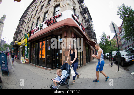 Eine Frau, die ein Baby in einem Kinderwagen schieben eine Miete Schild im Fenster einer geschlossenen Qdoba Mexican Grill Restaurant Stockfoto