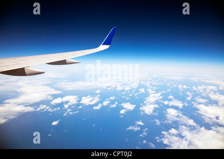 Blick aus Fenster Flugzeug heraus auf die Wolken und Krümmung der Erde und die Flügelspitze Flugzeug Stockfoto