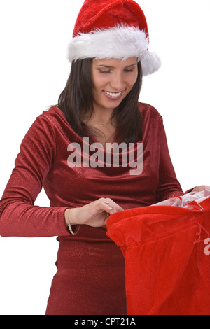 Junge Frau in roter Kleidung und Hut, die auf der Suche nach Geschenke in Santa es Sack. Stockfoto