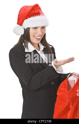 Glückliche junge Frau in einem roten Hut, Geschenke in Santa es Sack zu entdecken. Sie können Ihr Produkt auf ihre Handfläche legen. Stockfoto