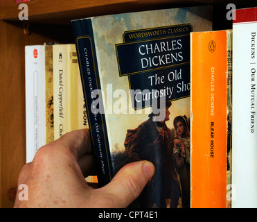Eine Hand unter Charles Dickens The Old Curiosity Shop von einem Bücherregal Stockfoto