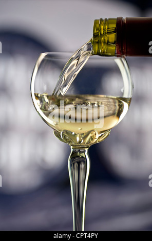Glas Weißwein Alsace in traditionellen verzierte lange stemmed Deco Glas mit Weinfässern hinter gießen Stockfoto