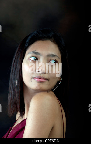 Die junge indonesische Frau posiert für ein Modeshooting in einem stilvollen Outfit in einer urbanen Umgebung mit natürlichem Licht und einem selbstbewussten Ausdruck Stockfoto