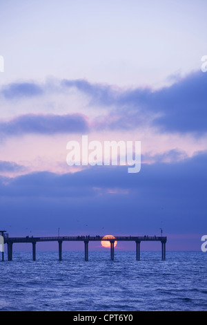 Untergehende Sonne knapp über dem Horizont am Ocean Beach Pier. San Diego, Kalifornien. Stockfoto