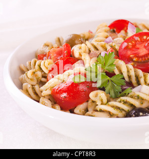 Fusili Nudelsalat mit Rucola-Pesto, saftige Tomaten, Oliven und Zwiebeln. Stockfoto