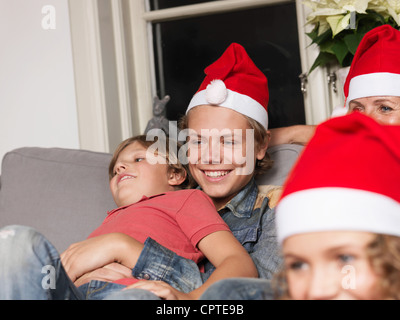 Familie Santa Hüte zu tragen, auf sofa Stockfoto