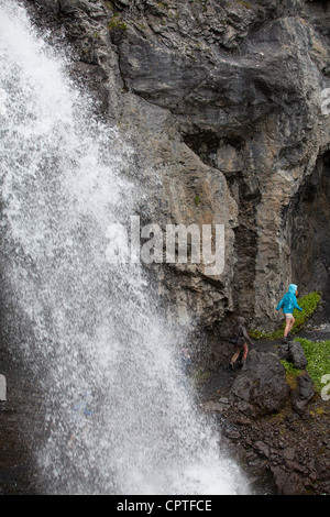 Kinder laufen hinter einem Wasserfall in Trafoi-Tal, Italien Stockfoto