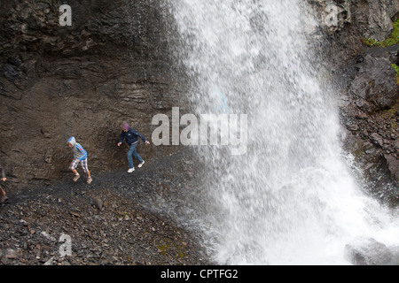 Kinder laufen hinter einem Wasserfall in Trafoi-Tal, Italien Stockfoto