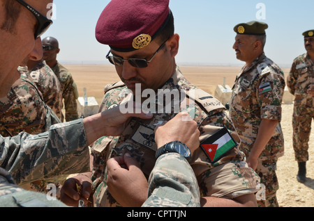 Ein US-Fallschirmspringer pinnt jordanische Sprungflügel an die Uniform eines jordanischen Streitkräftenparachutisten bei einer Formation, die nach Übung eifriger Löwe 2012 Freundschaftssprung gehalten wird. Der Sprung war Teil von Übung eifriger Löwe, einer multilateralen militärischen Übung, die auf die Stärkung der militärischen Beziehungen und die Förderung der Zusammenarbeit zwischen den teilnehmenden Nationen konzentriert war. Stockfoto