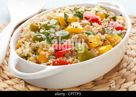 Couscous mit Kichererbsen, rote, grüne und gelbe Paprika, Zwiebeln, Kümmel und Petersilie, zubereitet mit Olivenöl extra vergine. Stockfoto